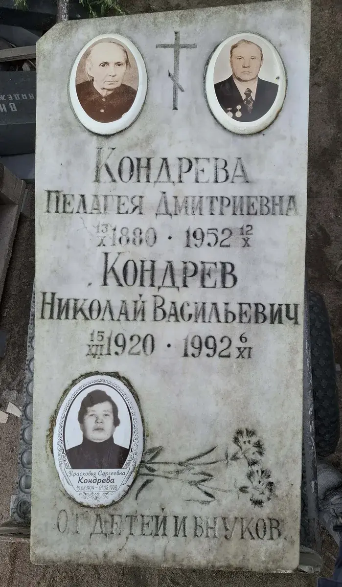 Светлая стела до обновления: три овальных фотопортрета, крест и прежние семейные надписи.