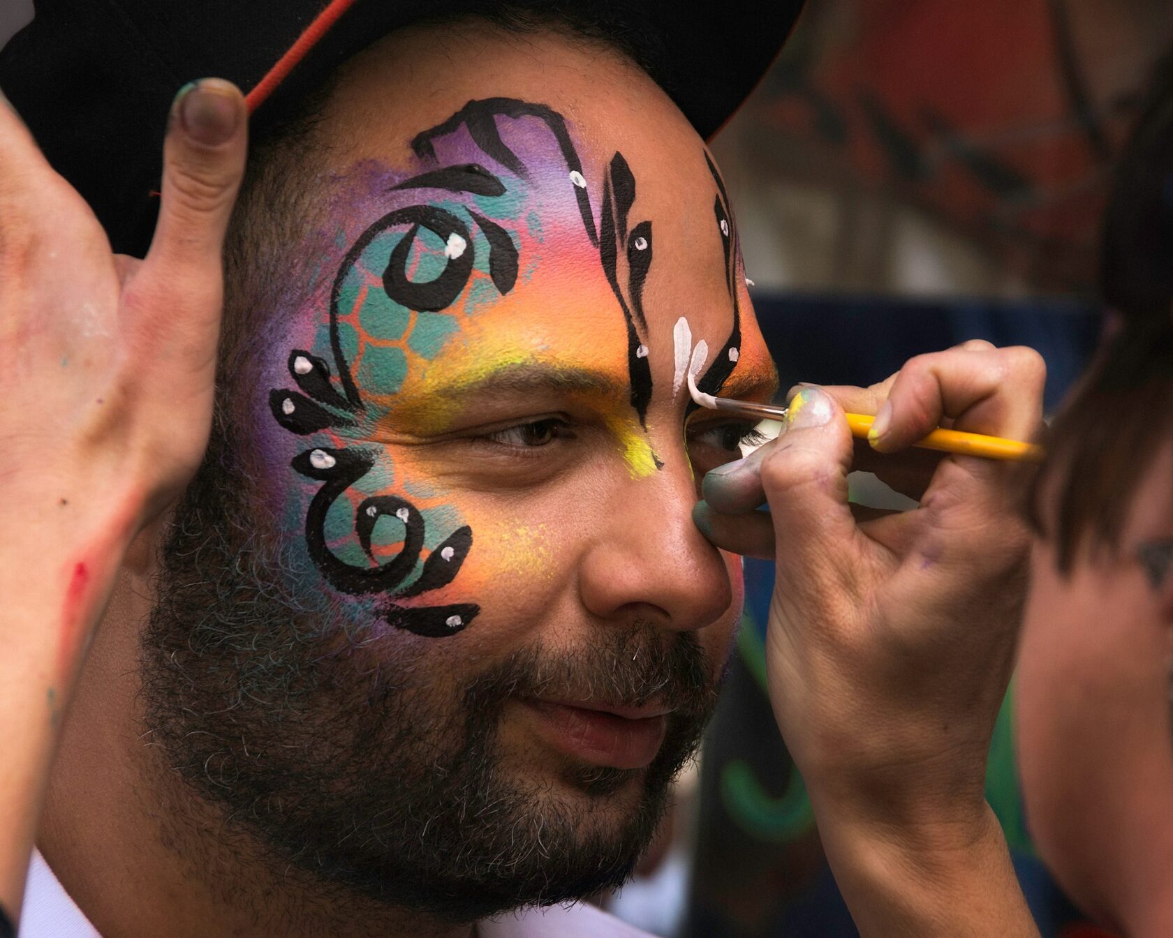 Intricate full-face painting artwork on an adult at a festival