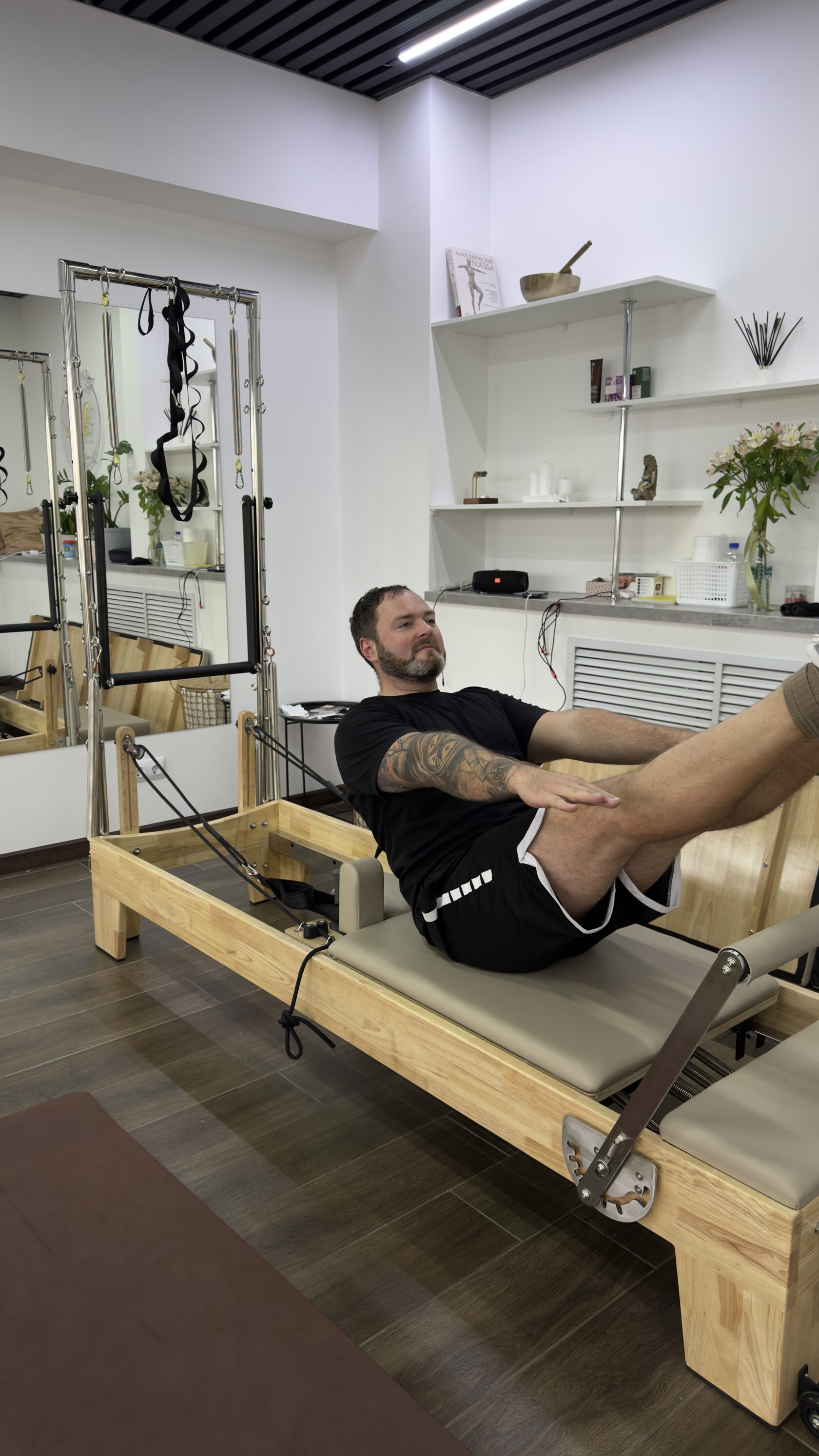Инструктор Андрей выполняет упражнение на реформере. Специалист по кинезиотейпированию, реабилитации после травм и оздоровительной физкультуре при болях в спине.