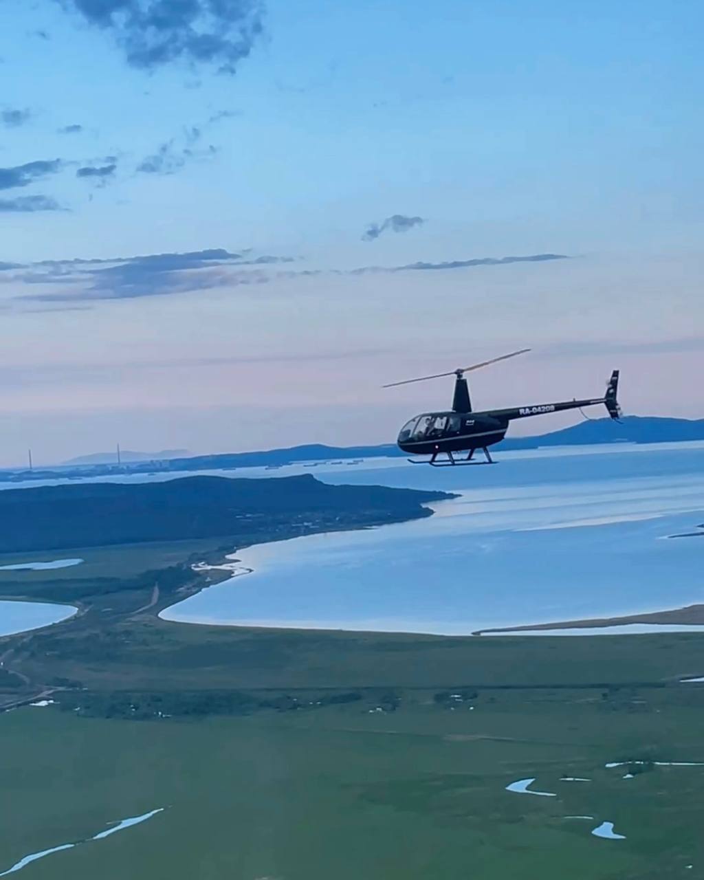 Вертолет в полете над лагуной и песчаной отмелью