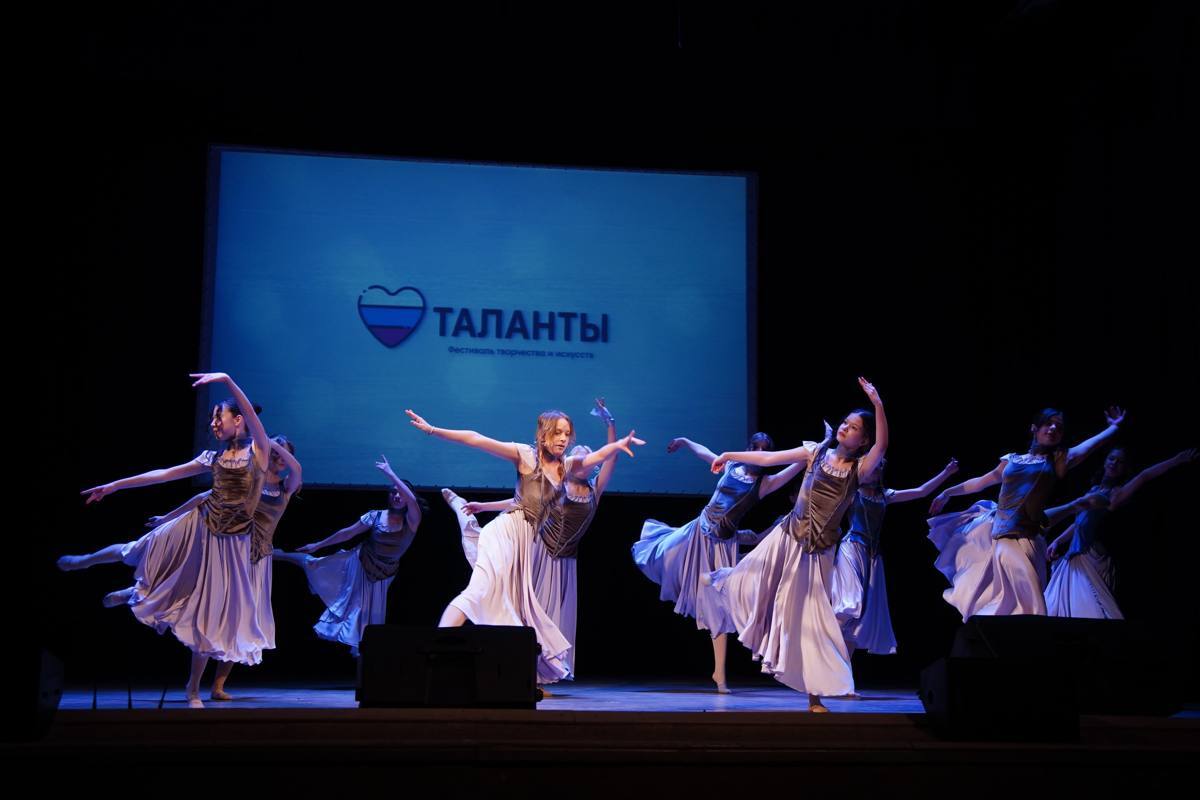 Танцевальный коллектив в светлых костюмах выступает на сцене фестиваля «Таланты»