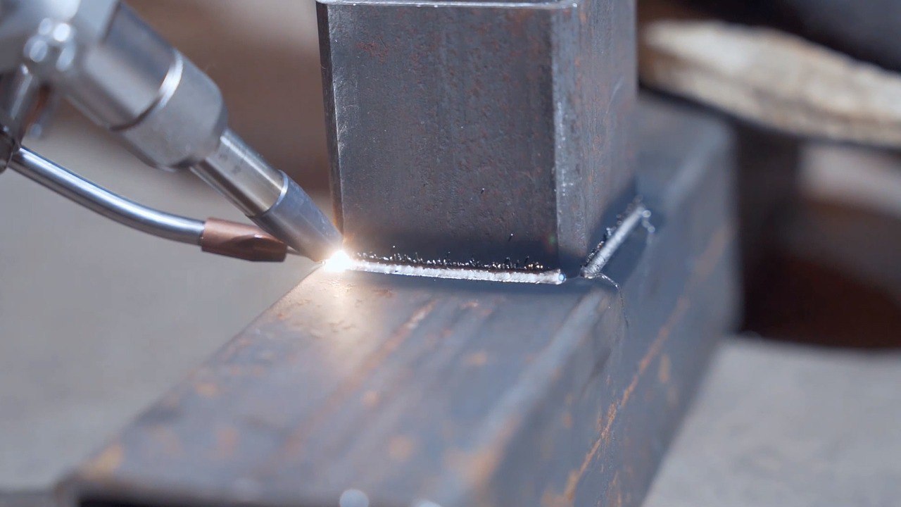 Сварщик использует сварочный пистолет для сварки двух металлических деталей