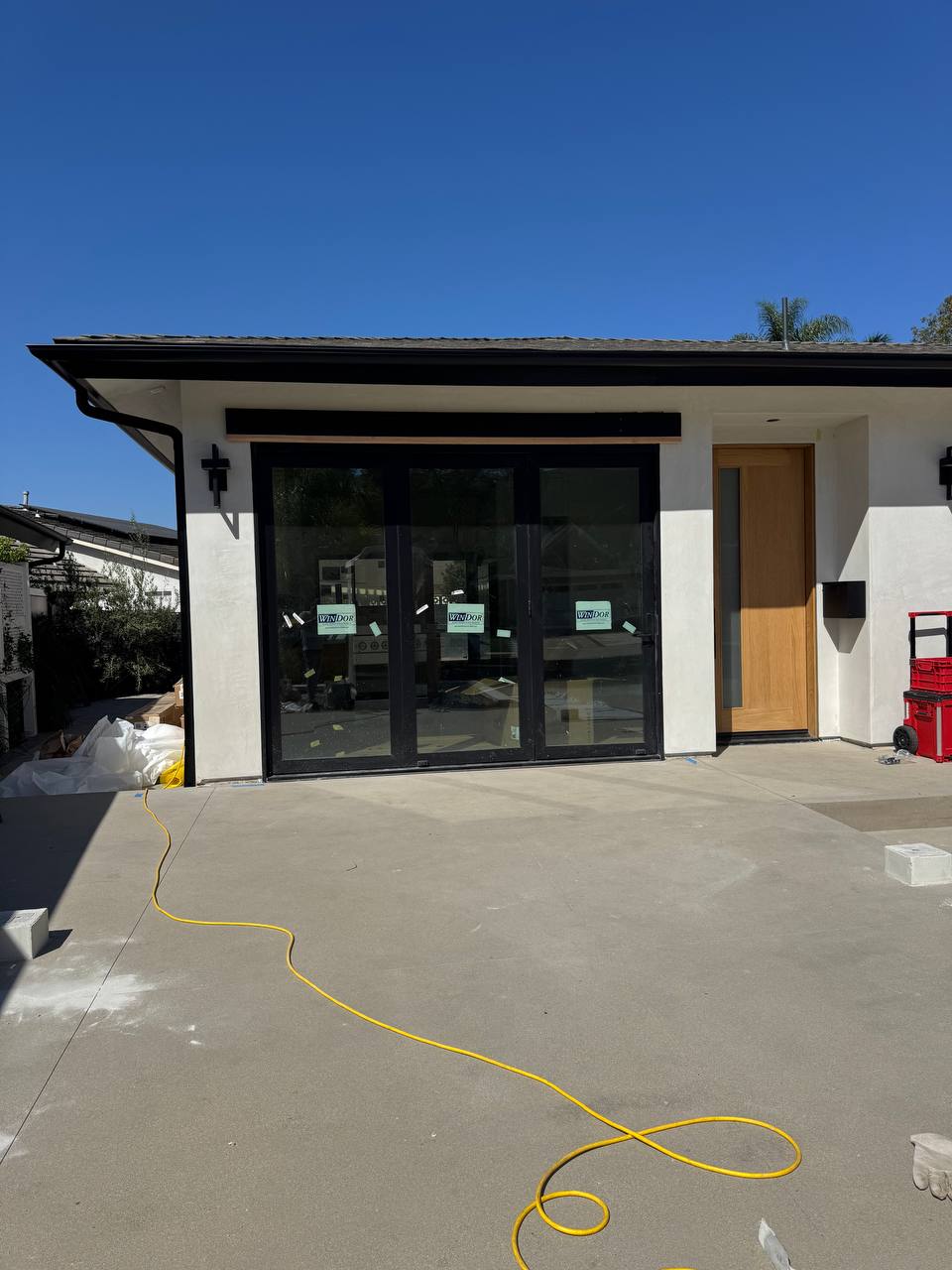 Front view of the uncovered concrete patio and black-framed glass doors before installation.