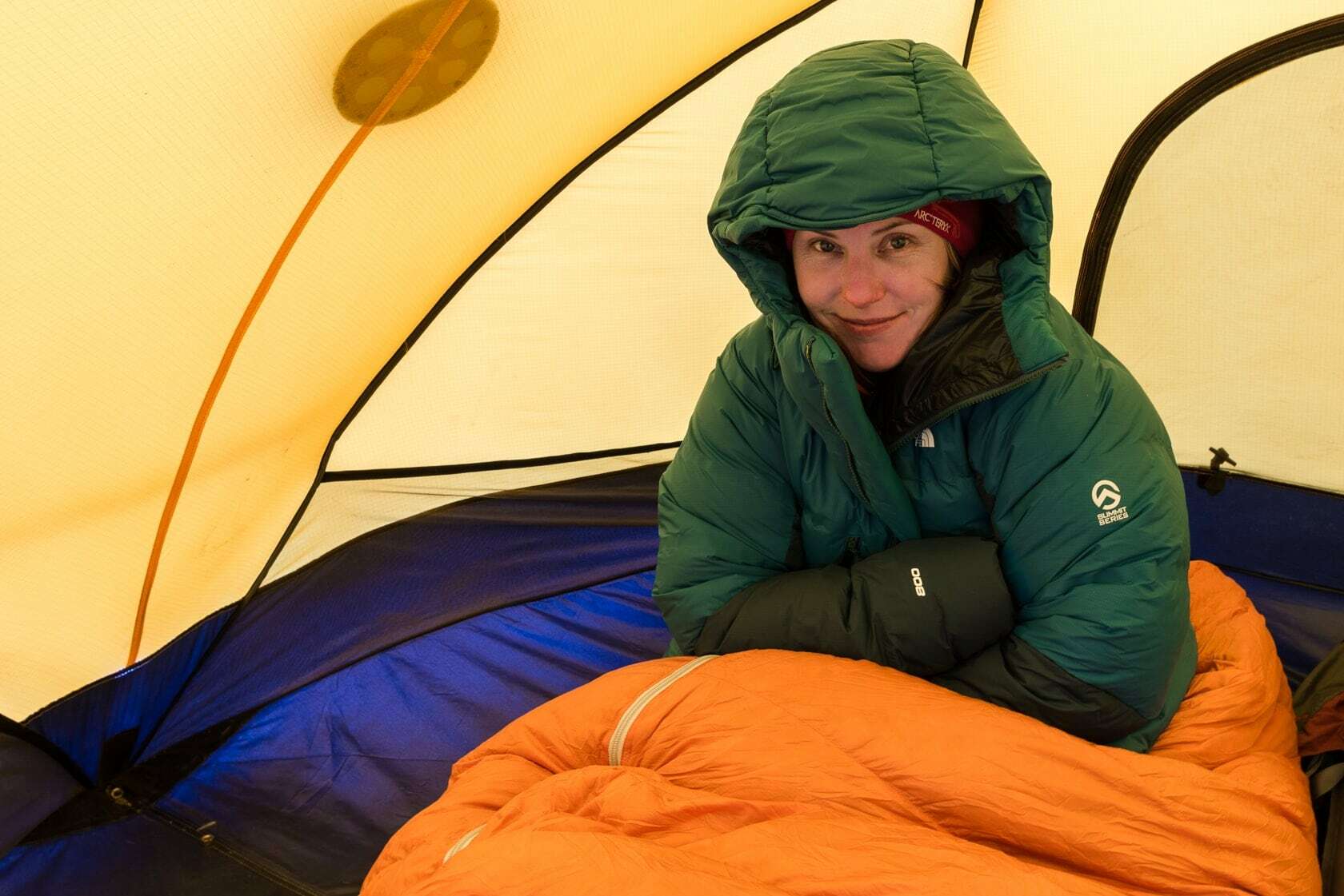 Альпинист сидит в палатке в спальном мешке