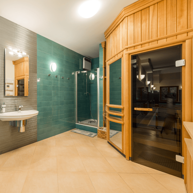 Eine vermutlich elektrische Innensauna, gleich daneben ist eine Duschkabine und ein Waschbecken zu sehen