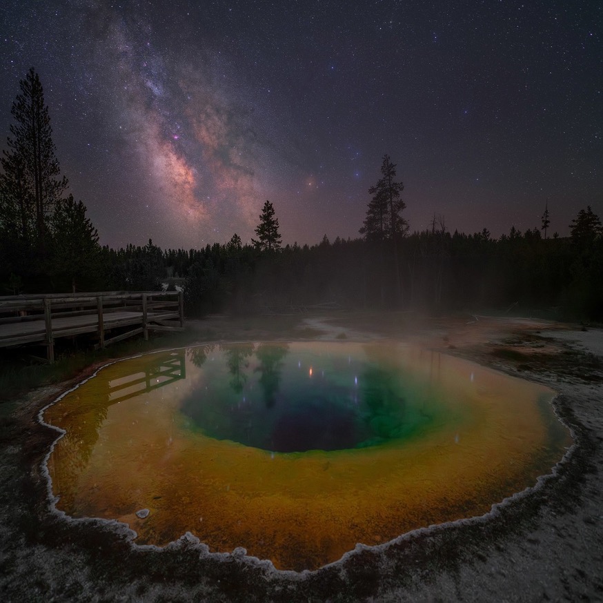 A colorful pool of water with a wooden bridge over it

Description automatically generated