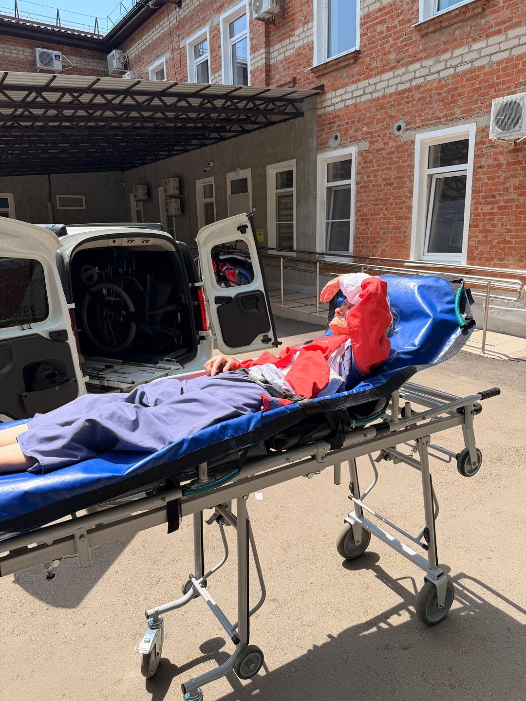 Пациент на каталке у больницы перед погрузкой в машину