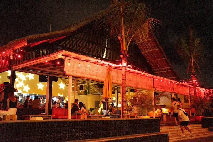 The lively, open-air setting at Old Man's Canggu under warm red string lights, a classic beachfront hangout and a staple among the best bars in Bali.
