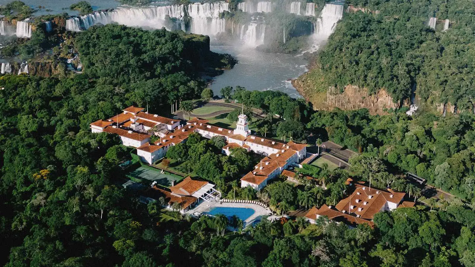 Розовый колониальный корпус Hotel das Cataratas Belmond и водопады Игуасу с высоты, Бразилия