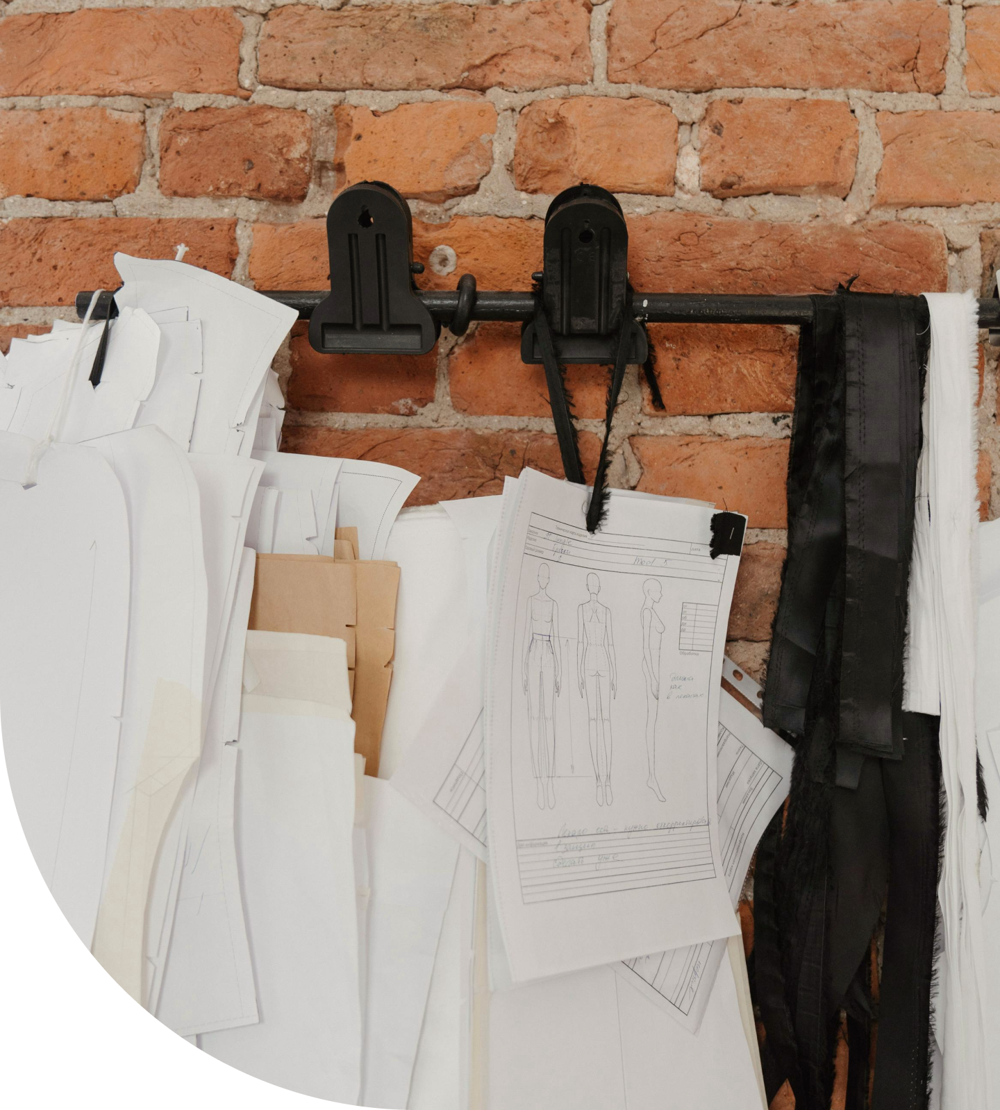 Кирпичная стена с крючками на которых висят лекала для одежды