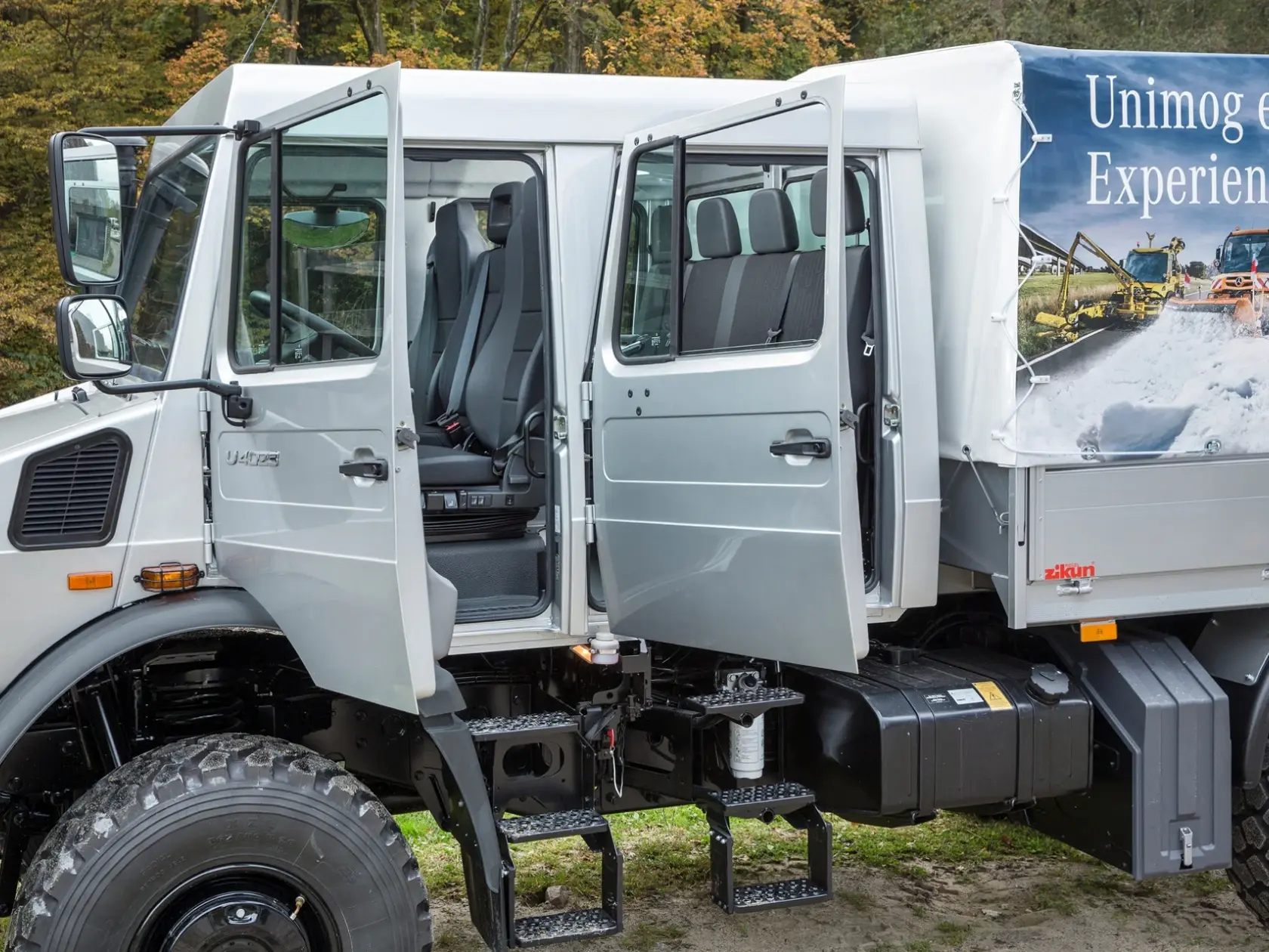 Серебристый Unimog с открытыми дверями: салон двойной кабины и сиденья