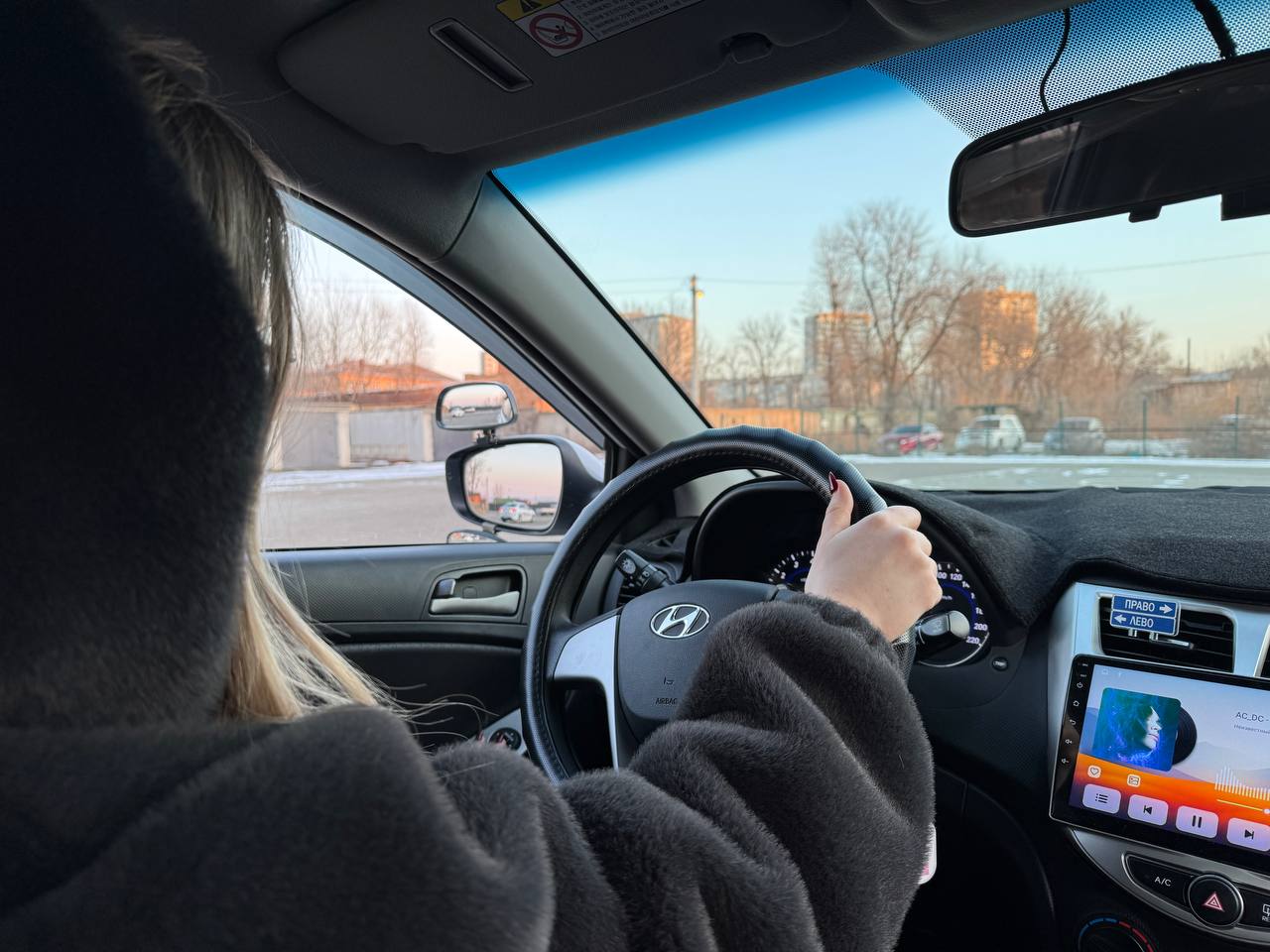 Черно-бронзовый мотоцикл стоит на стоянке у серого бетонного здания, вид сбоку