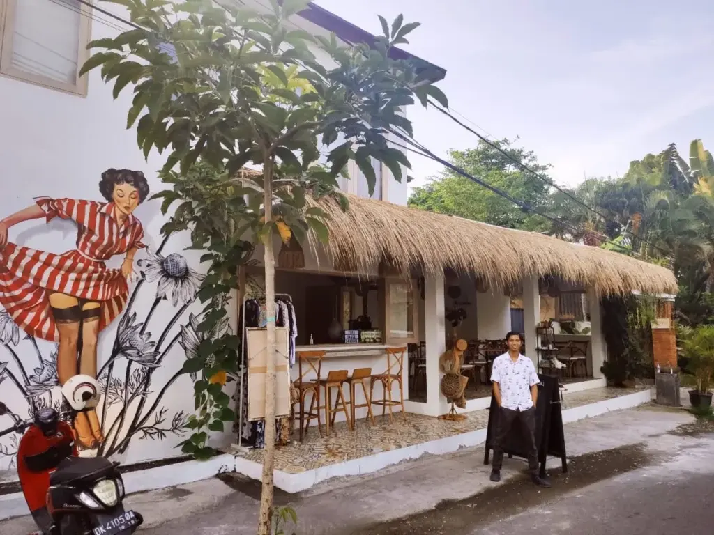 The quirky exterior of a Canggu eatery featuring a vintage pin-up mural and a traditional thatched roof, a popular destination for affordable and delicious Russian food in Bali