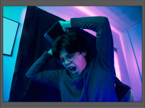 Молодой человек в очках кричит и размахивает клавиатурой, собираясь ударить.