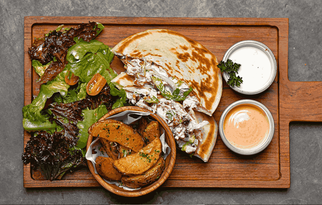 Grilled wraps served on a wooden board with sauces, showcasing the variety of modern halal food in Ubud at Eden Lounge.