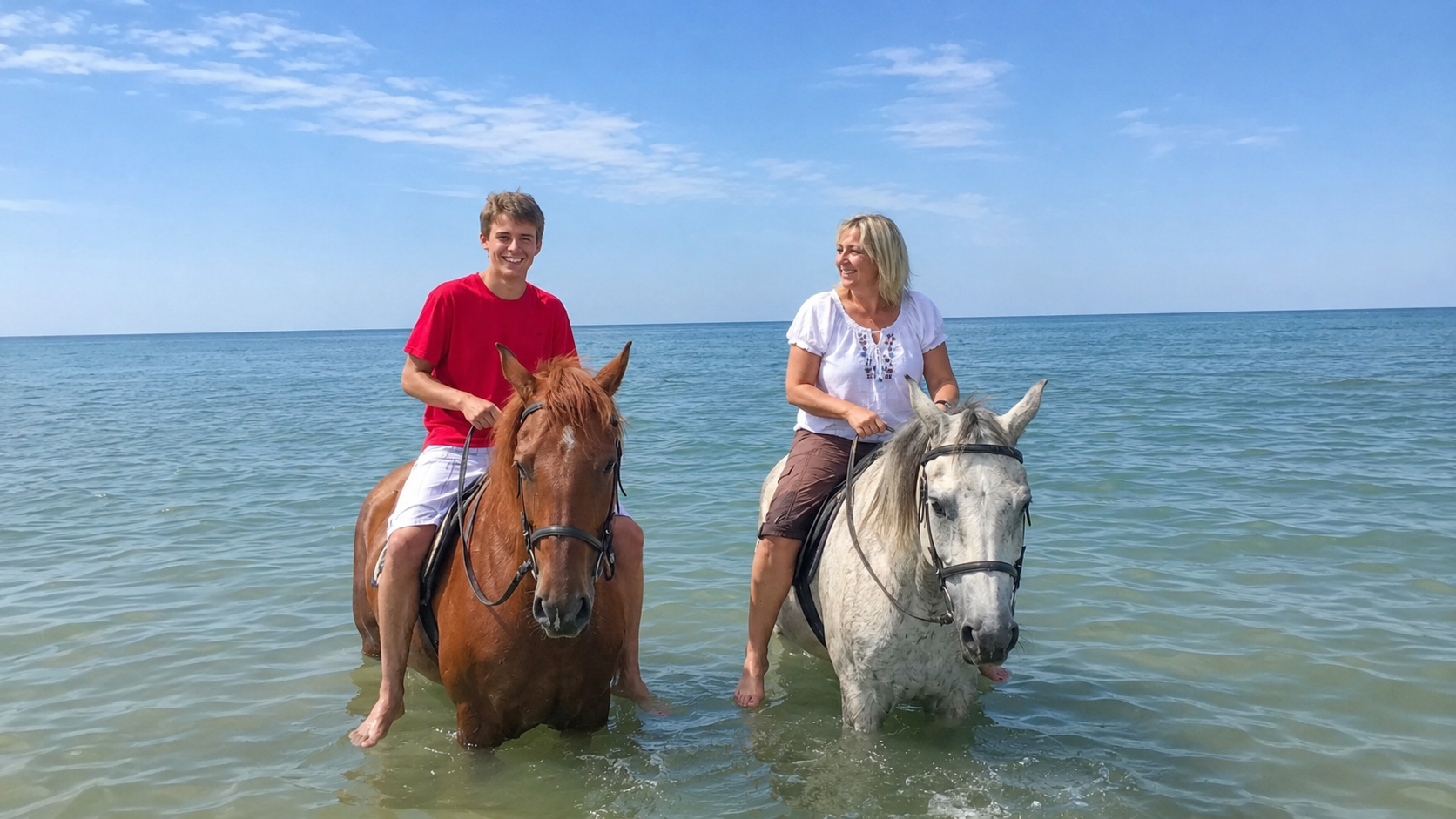 Парень и женщина верхом на лошадях в воде на побережье Азовского моря в Должанской