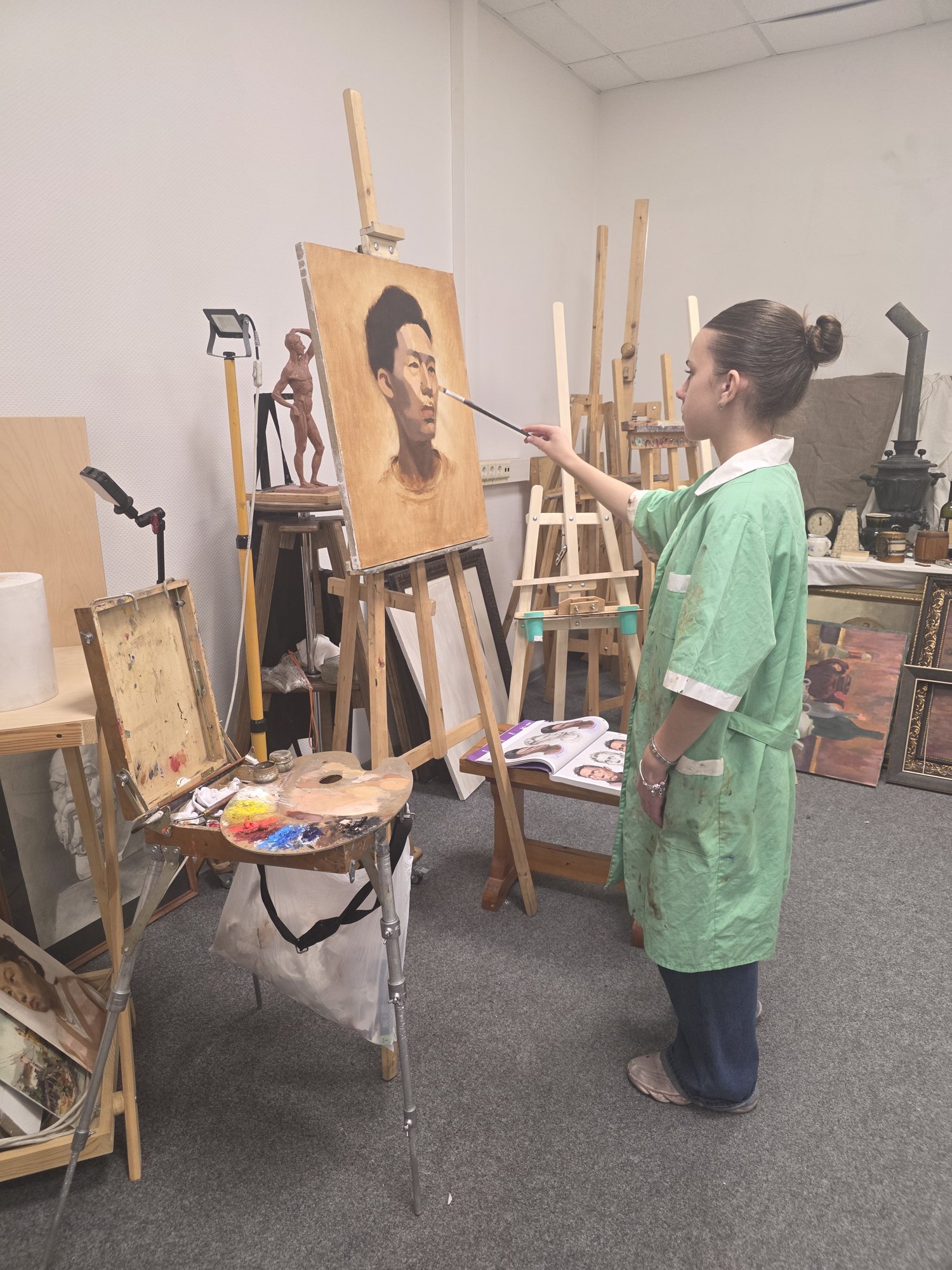 Ученица пишет маслом мужской портрет за мольбертом в мастерской ABC Art School