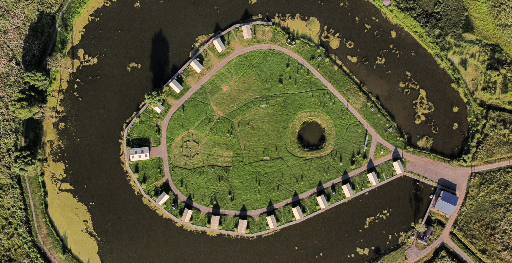 The island at Ostrov Glamping ringed by water, seen from above