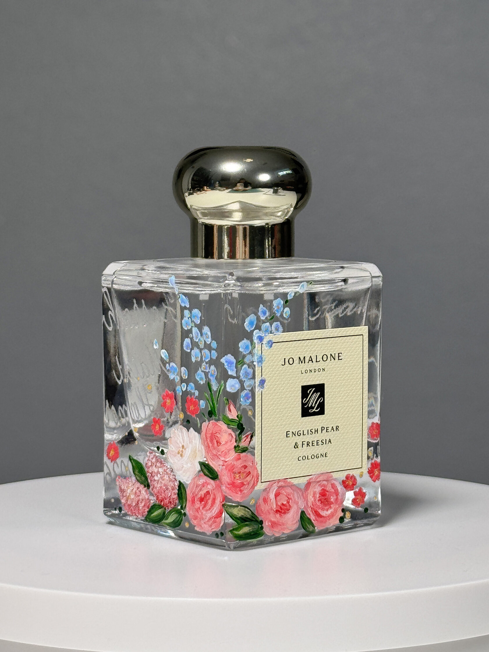 Finished custom hand-painted Jo Malone perfume bottle with vibrant pink roses and blue flowers by Julia Razz.