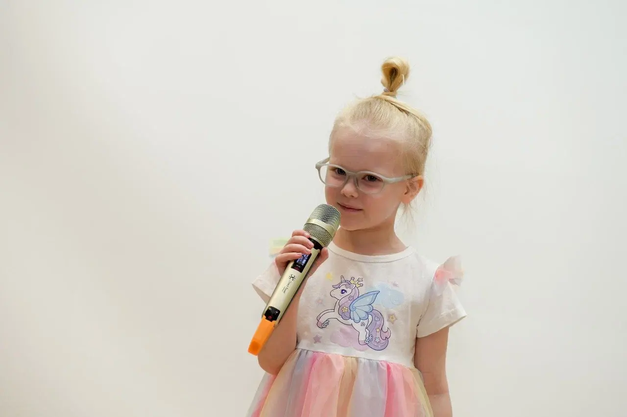 Маленькая девочка поет в микрофон