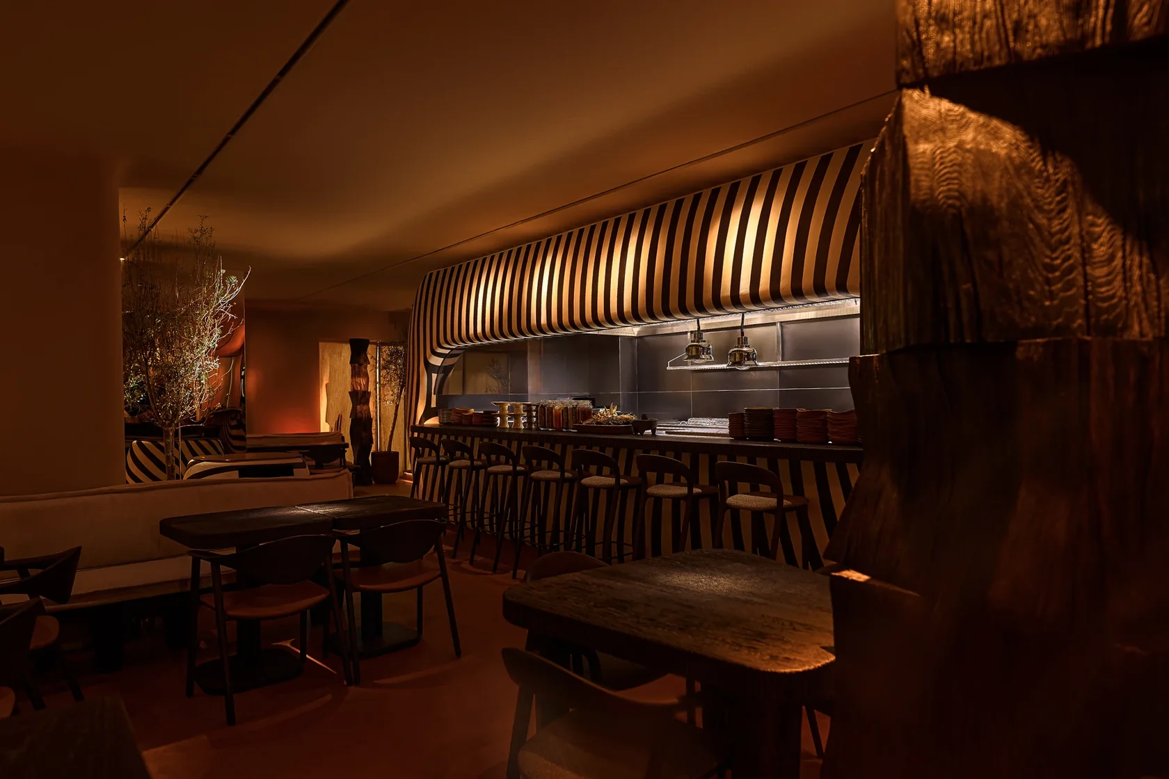 The dining room, intimate tables and illuminated striped bar at Sobremesa