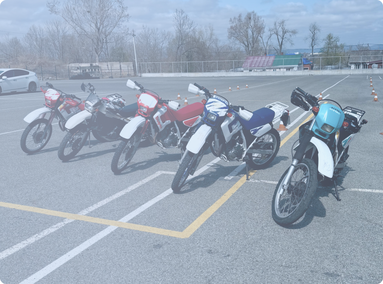 Черно-бронзовый мотоцикл стоит на стоянке у серого бетонного здания, вид сбоку