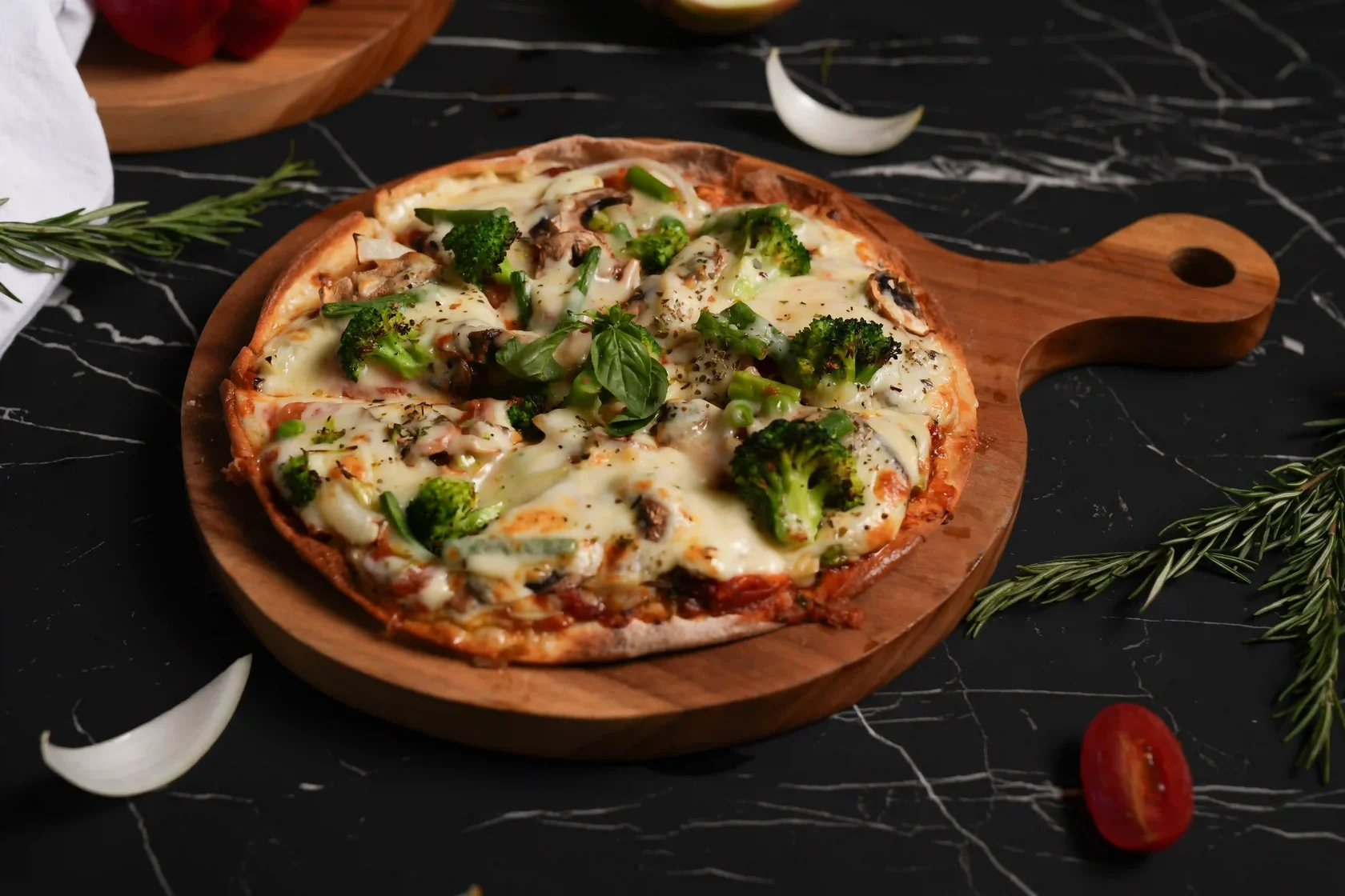 A tasty, freshly baked vegetarian pizza topped with broccoli and mushrooms served on a dark marble surface.