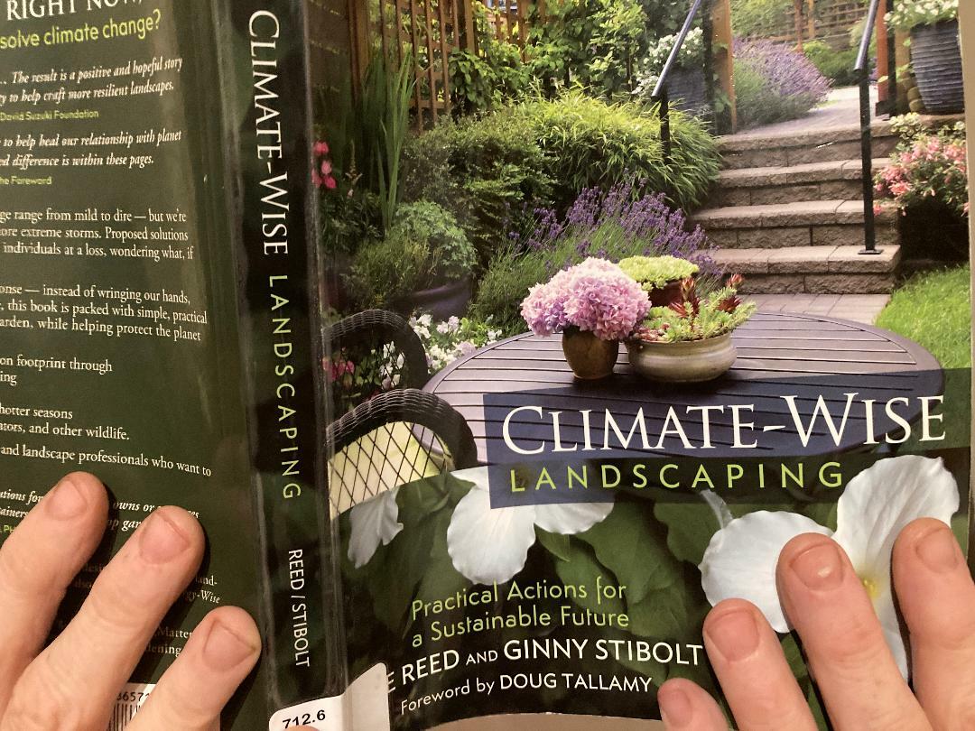 Close-up of two hands holding a book. The book&amp;#39;s title is &amp;amp;quot;Climate-wise Landscaping.&amp;amp;quot;