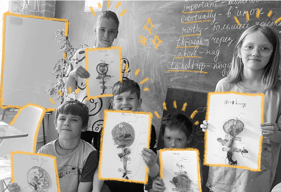 ученики подростки в учебном классе показывают свои нарисованные картины на фоне доски с мелом с английскими словами