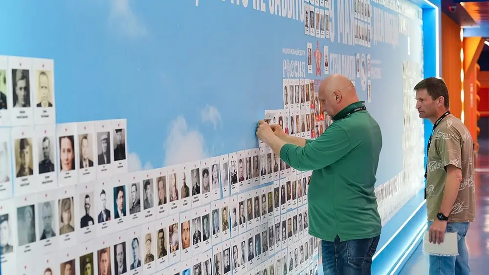 Посетители размещают фотографии ветеранов Великой Отечественной войны на стенде акции «Стена Памяти» в Национальном центре «Россия».
