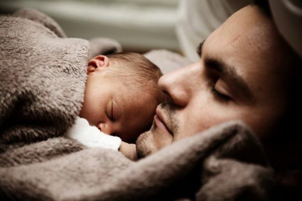 Un papà riposa con il suo bimbo appena nato tra le braccia