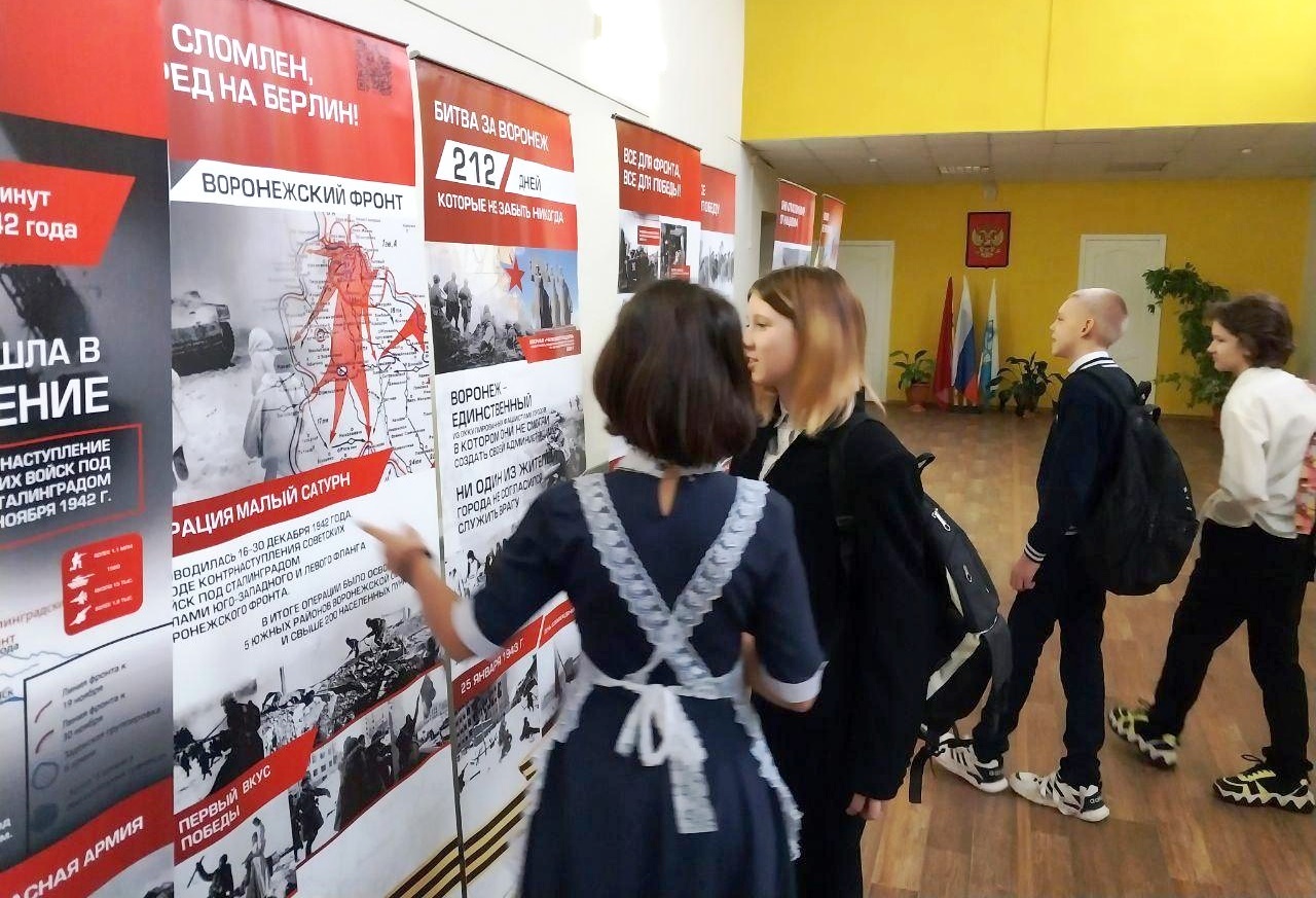Дети смотрят стенд с героями СВО