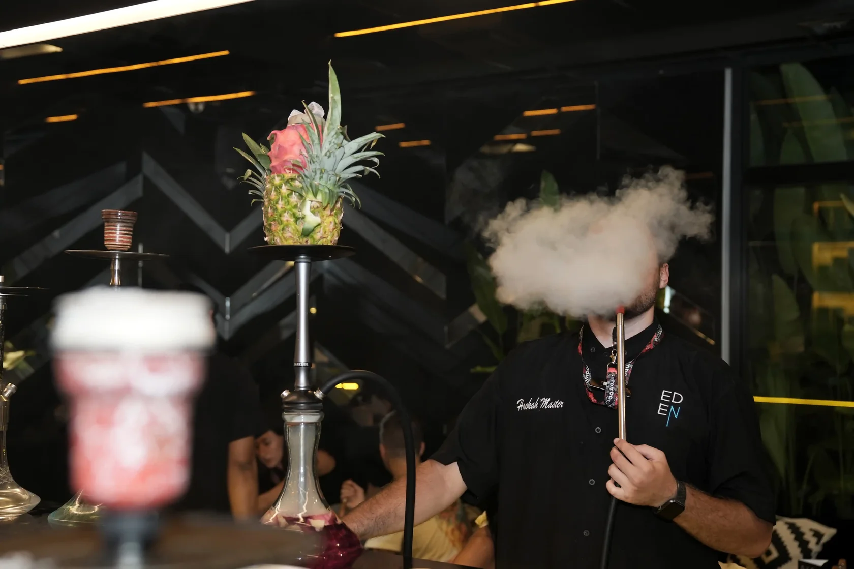 Shisha master preparing a hookah bowl with a poker tool demonstrating how to manage nicotine level in shisha through proper bowl preparation.