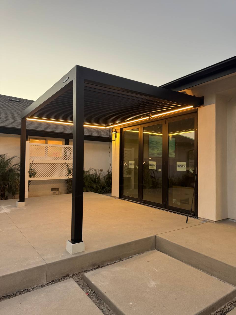Warm LED strips illuminate the attached pergola and patio at sunset.