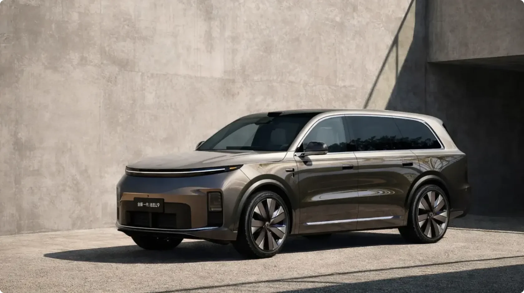 Второе поколение флагманского кроссовера Li Auto L9 в цвете бронзовый металлик, вид спереди сбоку в урбанистической локации: обновленная светодиодная оптика, лидар на крыше, утопленные ручки и новые аэродинамические диски
