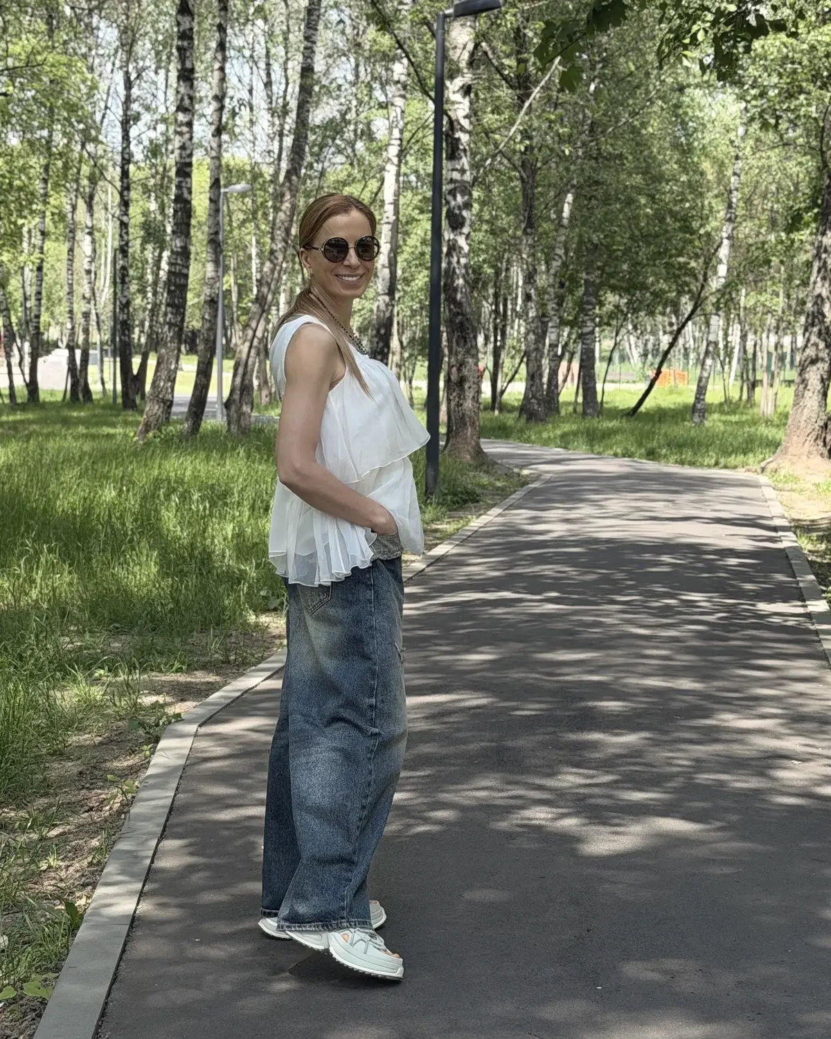 Эльвира смотрит вверх, стоя у дерева