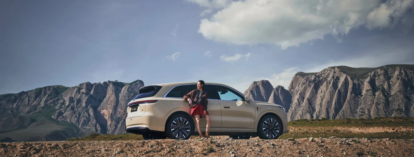 Li Auto L6 песочного цвета на фоне гор, рядом женщина