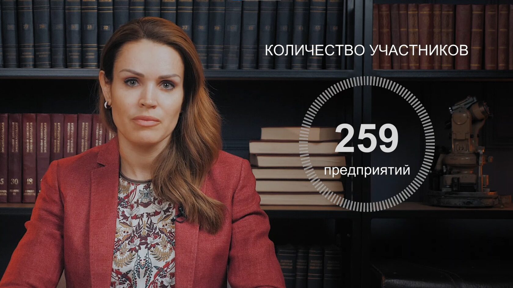 Женщина в красном пиджаке с инфографикой на экране.