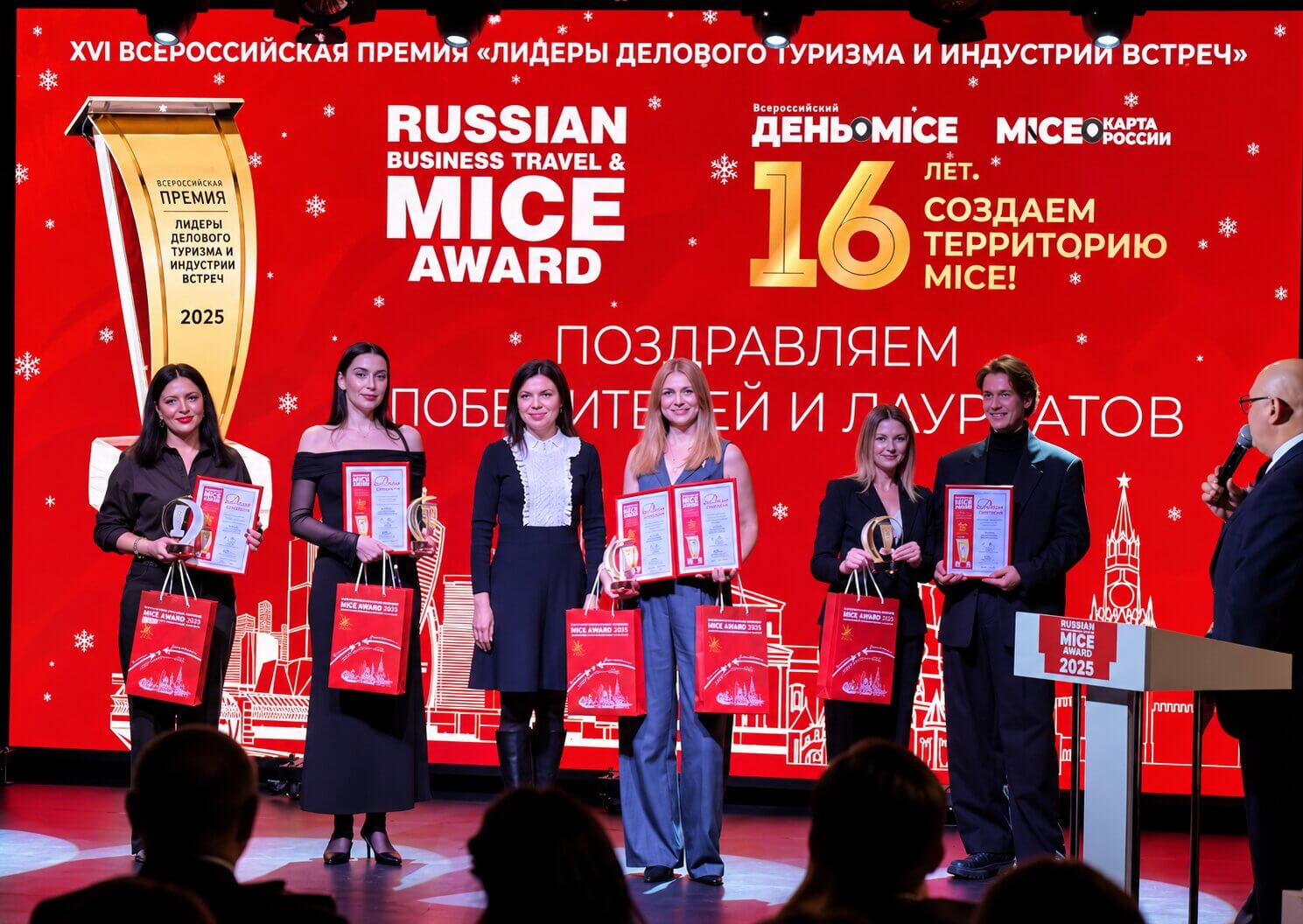 Награждение победителей премии Russian Business Travel  MICE Award 2025 на сцене на фоне красного баннера с надписью Поздравляем победителей и лауреатов.