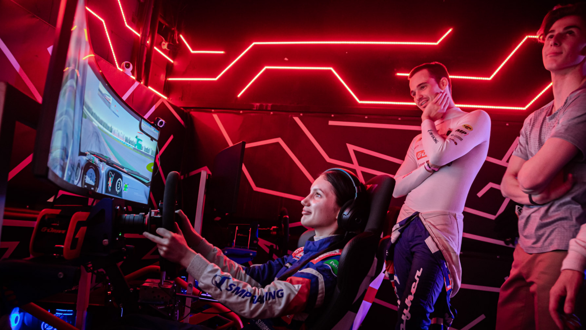 Момент, когда друзья смотрят, как девушка проходит виртуальную трассу, быстрее, чем они