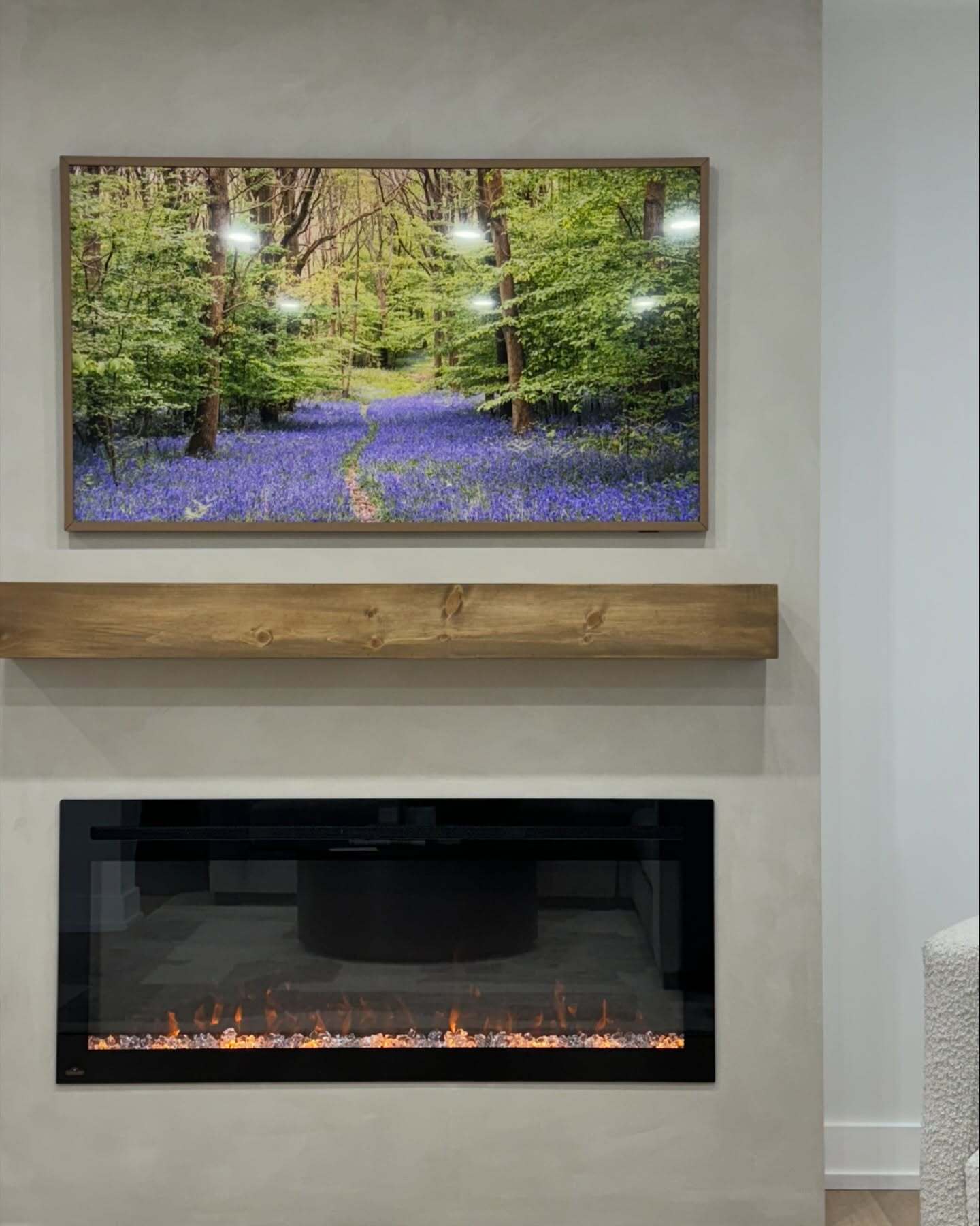 Front view of a recessed fireplace beneath a wood mantel and framed display.