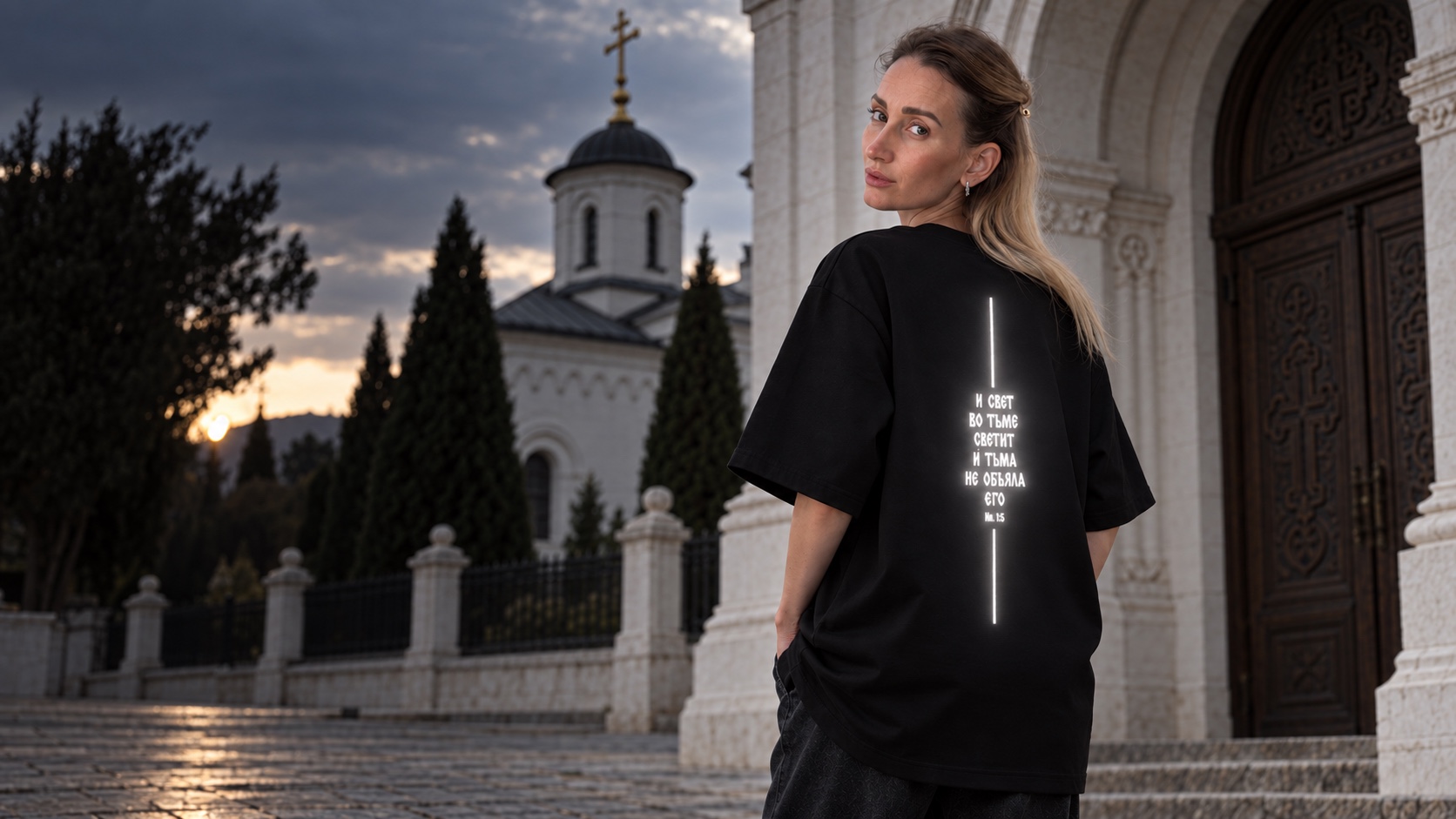 Женщина в чёрной футболке со спины, рефлективный принт проявляется под вспышкой