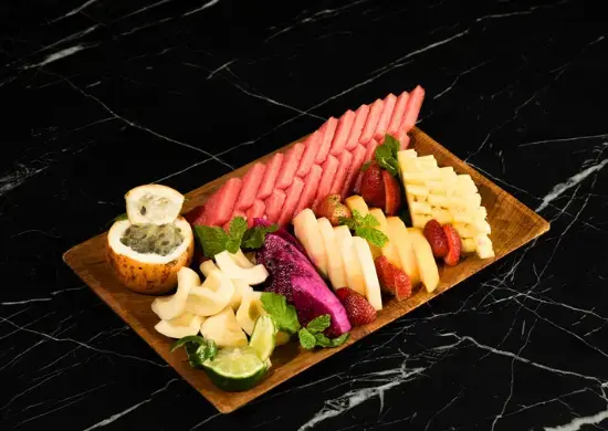 A wooden tray loaded with neatly sliced fresh tropical fruits, including watermelon, dragon fruit, melon, strawberries, snake fruit, and passion fruit. A refreshing palate cleanser for a Ramadan dinner in Ubud.