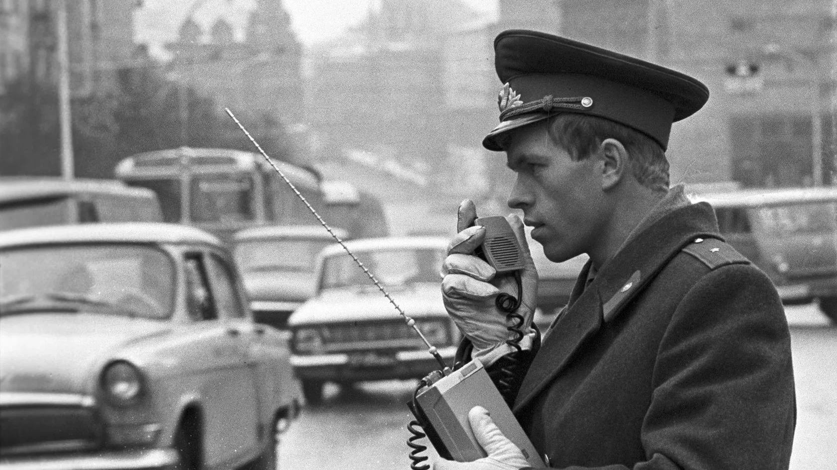 Советский милиционер с рацией стоит около патрульного автомобиля ГАЗ-21 Волга, историческое фото.