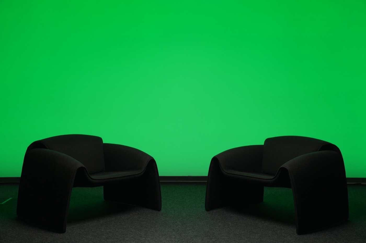 Green screen wall set to chroma-key green with two lounge chairs