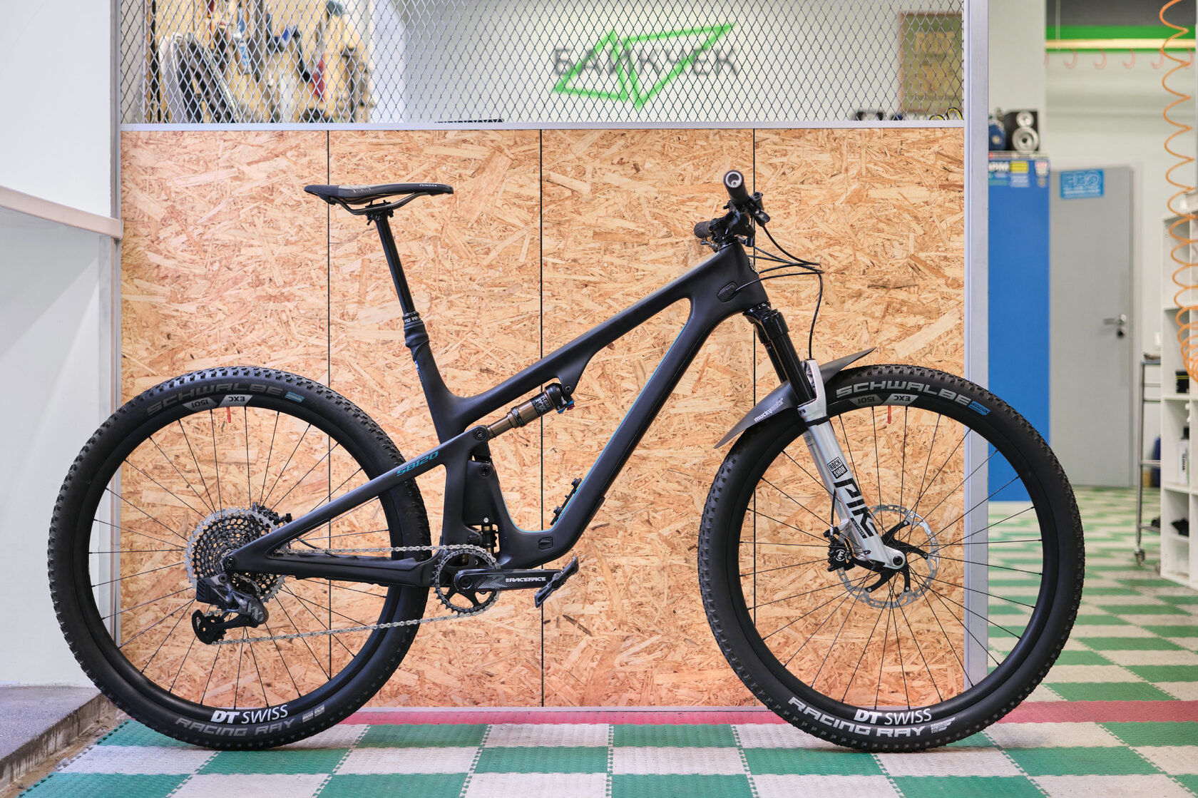 Черный двухподвес с вилкой RockShox Pike в мастерской у деревянной перегородки