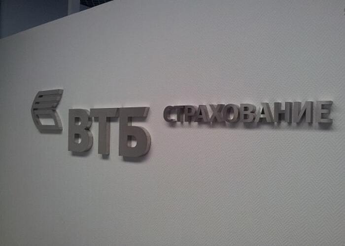 Объёмный логотип и надпись ВТБ страхование на серой интерьерной стене