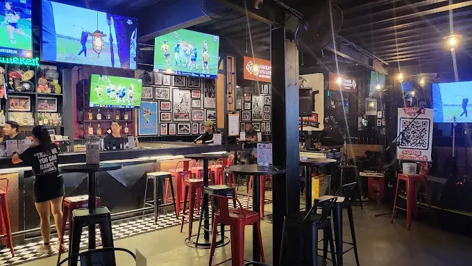 Patrons hanging out at the bar and watching sports on screens inside The Goat, a lively pub and late night lounge in Seminyak.