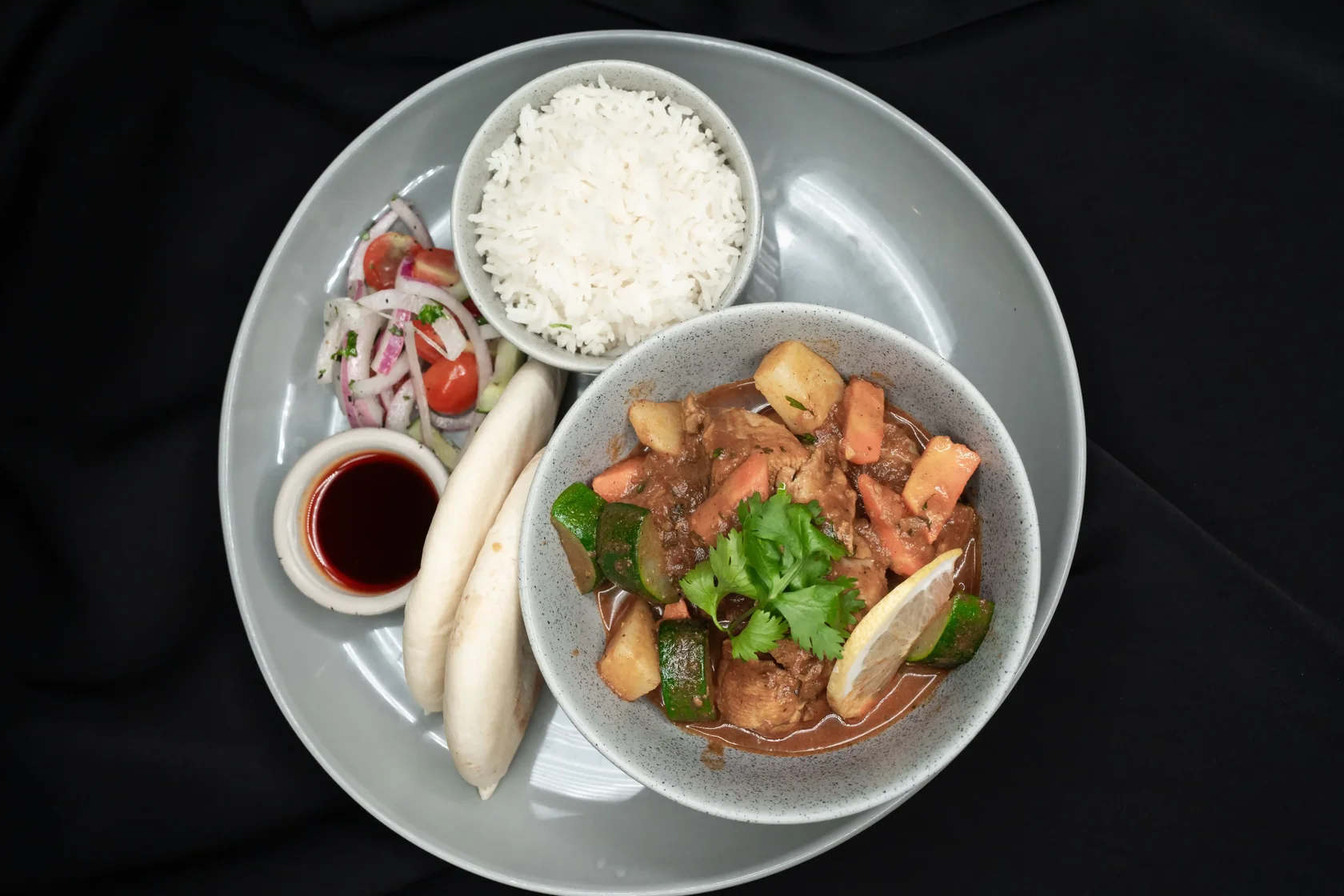 Chicken Salona served with Arabic tomato chicken curry with zucchini, carrot, and potatoes. Served with basmati rice, pita bread, and cucumber salad