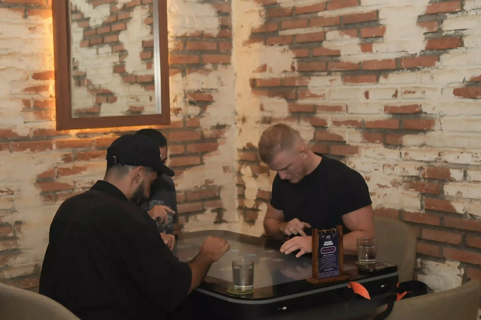Three friends completely absorbed in a high-tech digital gaming table, finding an exciting and unique way to bond in this complete Bali Nightlife Guide.